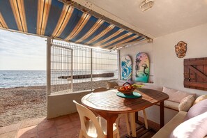 Een terras aan het strand met een tafel, stoelen en uitzicht op zee.