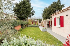 Il s’agit d’une propriété résidentielle dotée d’un jardin bien entretenu, d’un patio et d’un petit espace extérieur aménagé pour s’asseoir.