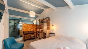 Un dormitorio moderno con cama, una silla azul, un escritorio de madera y un armario.