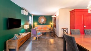 Una sala de estar con sofá, televisor, consola de madera y una mesa de comedor con sillas.