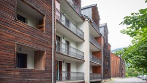 Ein mehrgeschossiges Gebäude mit Balkonen, einer Holzfassade und Blick auf die Straße.