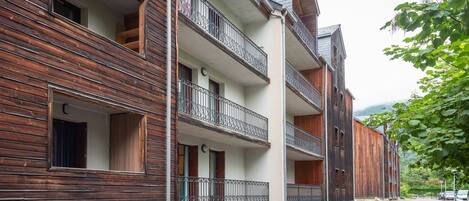 Un immeuble à plusieurs étages doté de balcons, d’une façade en bois et donnant sur la rue.