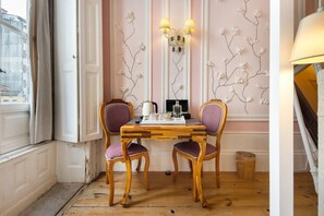 Un coin repas comprenant une table en bois, deux chaises, un miroir et un mur orné de motifs floraux.