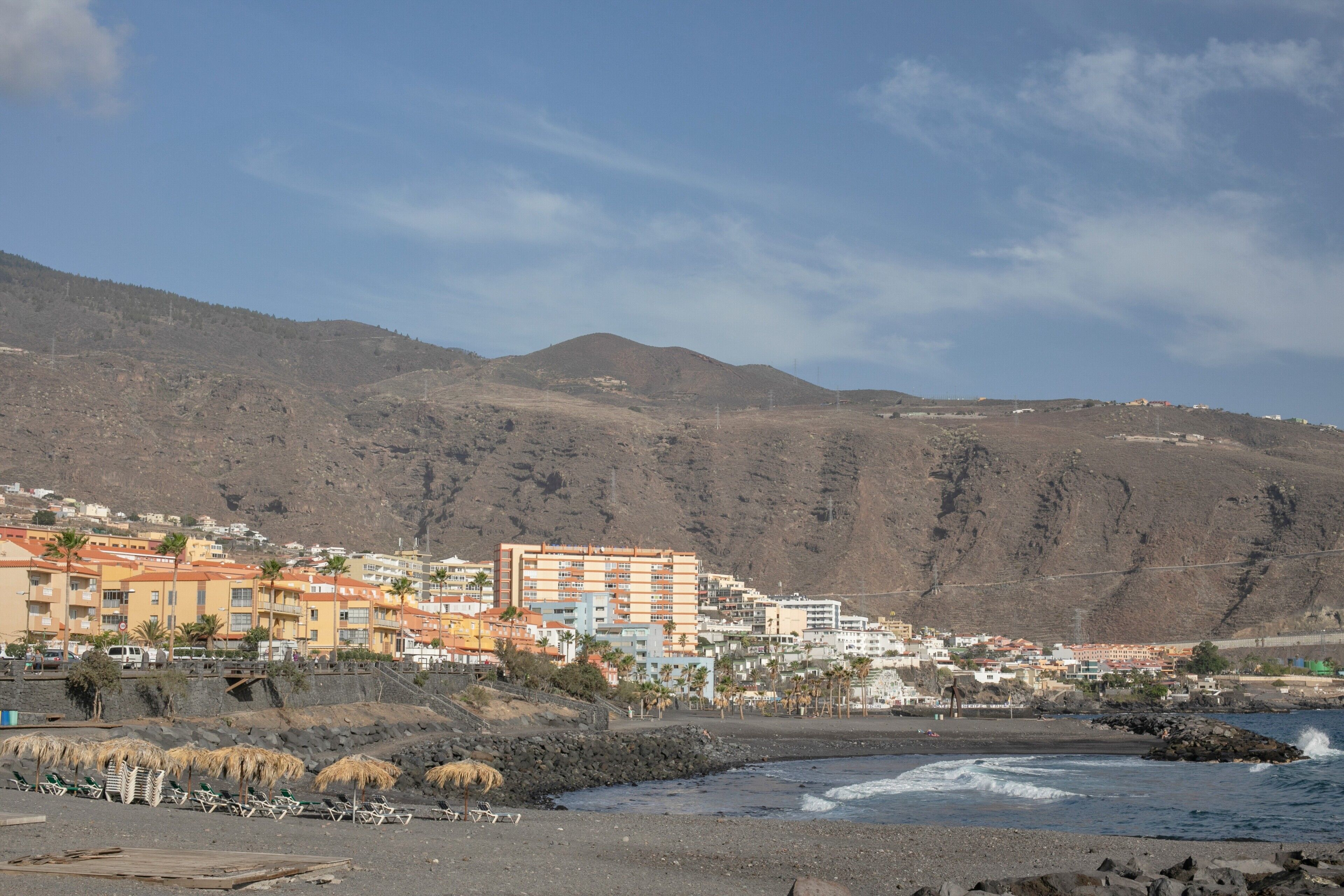 Une ville côtière avec des bâtiments, une plage et des montagnes en arrière-plan.
