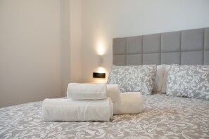 Un lit bien fait, avec une couvre-lit à motifs, une tête de lit et un luminaire fixé au mur.