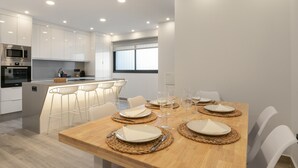 A modern kitchen with white cabinets, a built-in microwave, and a dining area with a wooden table set for four. - Vacation 'Avenida Marítima' with Sea View, Wi-Fi and Air Conditioning (Candelaria)