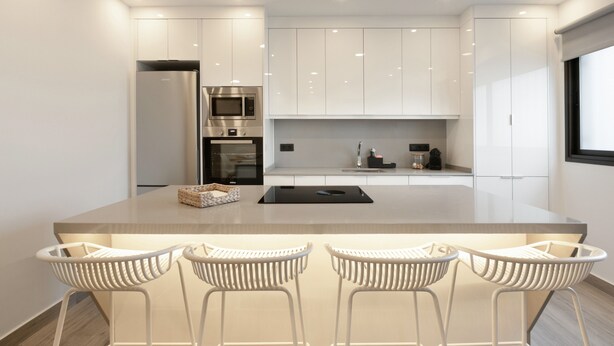 A modern kitchen with white cabinets, a central island with bar stools, a built-in oven, and a microwave. - Vacation 'Avenida Marítima' with Sea View, Wi-Fi and Air Conditioning (Candelaria)