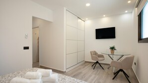 A modern hotel room with a bed, a TV, a small table with chairs, and a sliding door closet. - Vacation 'Avenida Marítima' with Sea View, Wi-Fi and Air Conditioning (Candelaria)