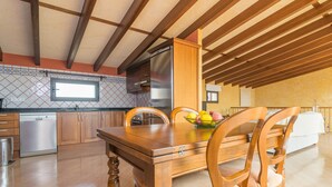 A kitchen with wooden cabinets, a stainless steel refrigerator, a dishwasher, and a dining table with chairs. - Holiday Home 'Can Nadal - Adults Only' with Mountain View, Wi-Fi and Air Conditioning (Sineu)