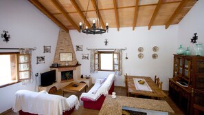 Una sala acogedora con chimenea, un sofá, un televisor y una mesa de comedor.