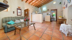 A spacious living area with a sofa, coffee table, and kitchen in the background. - Villa 'Sa Plana Ref 42' with Mountain View, Private Pool and Wi-Fi (Cala Bona)