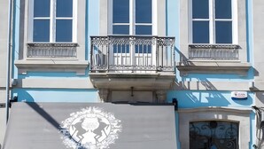 Un edificio de dos pisos con balcón, toldo y zona de estar al aire libre.