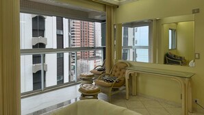 Un baño con un ventanal grande, una silla, un tocador y una bañera.
