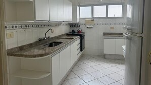 Una cocina con gabinetes blancos, encimera de granito, fregadero, estufa y refrigerador.