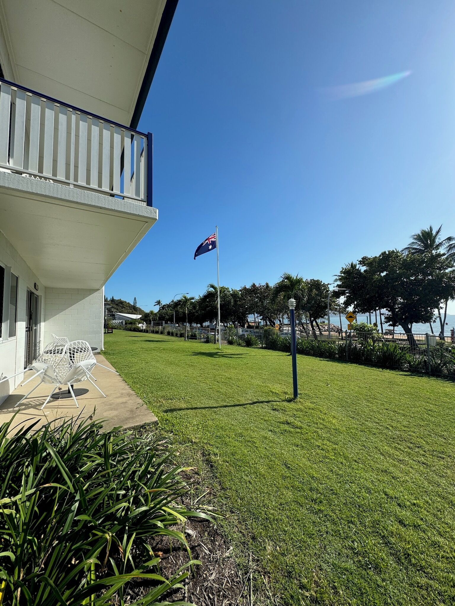 A building with a balcony, a flag, and a well-maintained lawn.