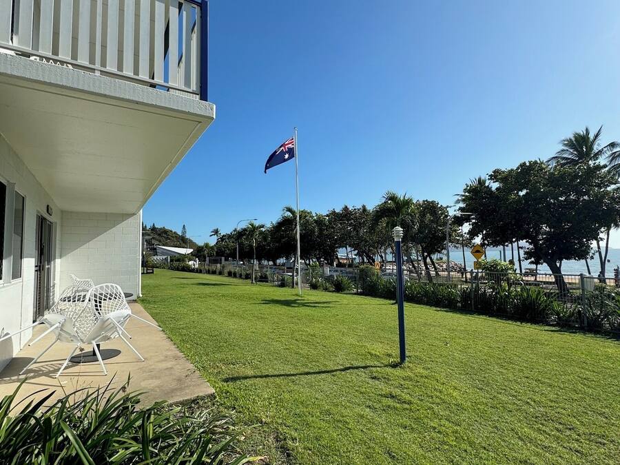 A building with a balcony, a flag, and a well-maintained lawn.