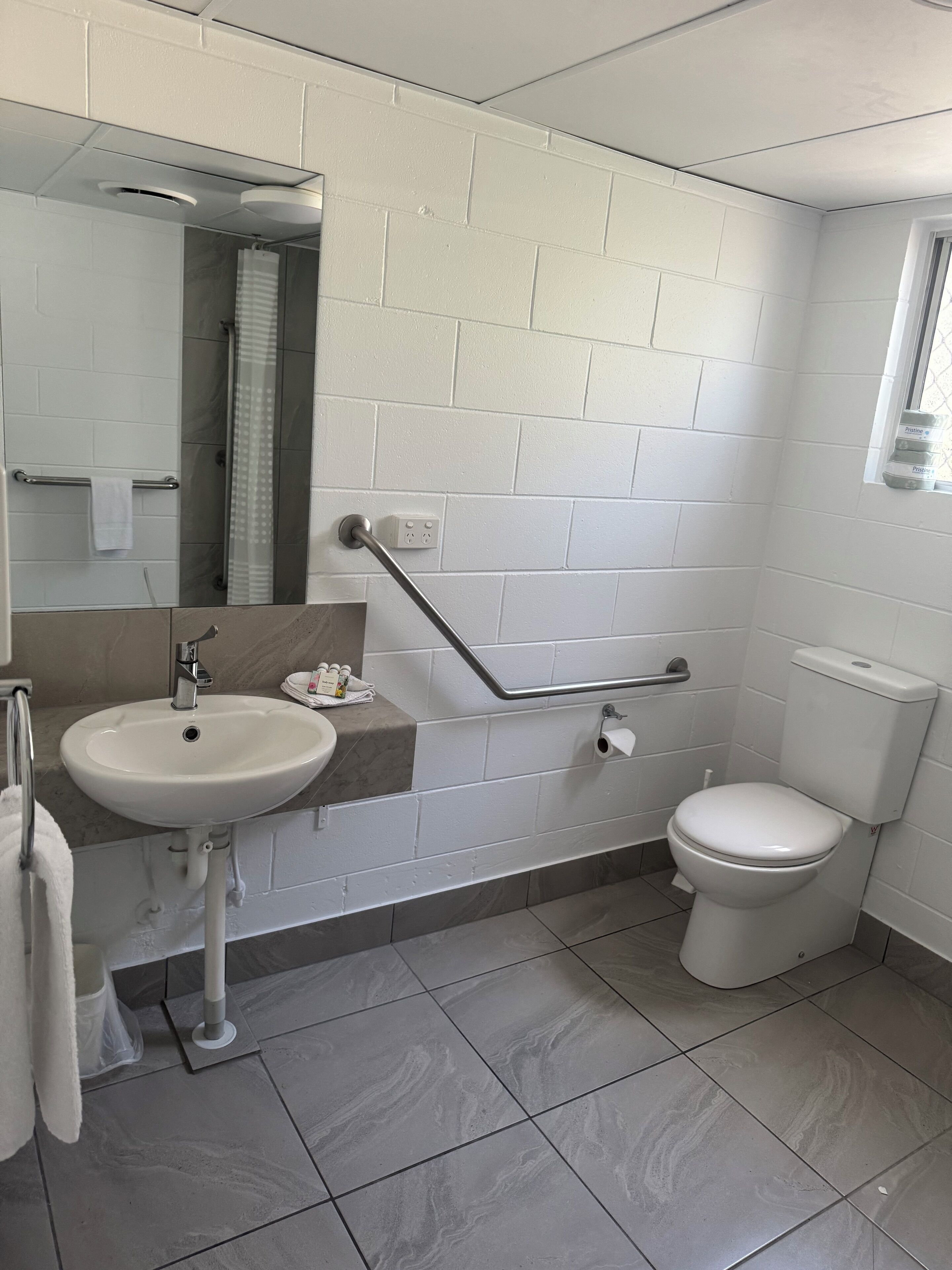 A bathroom with a white sink, mirror, and toilet.