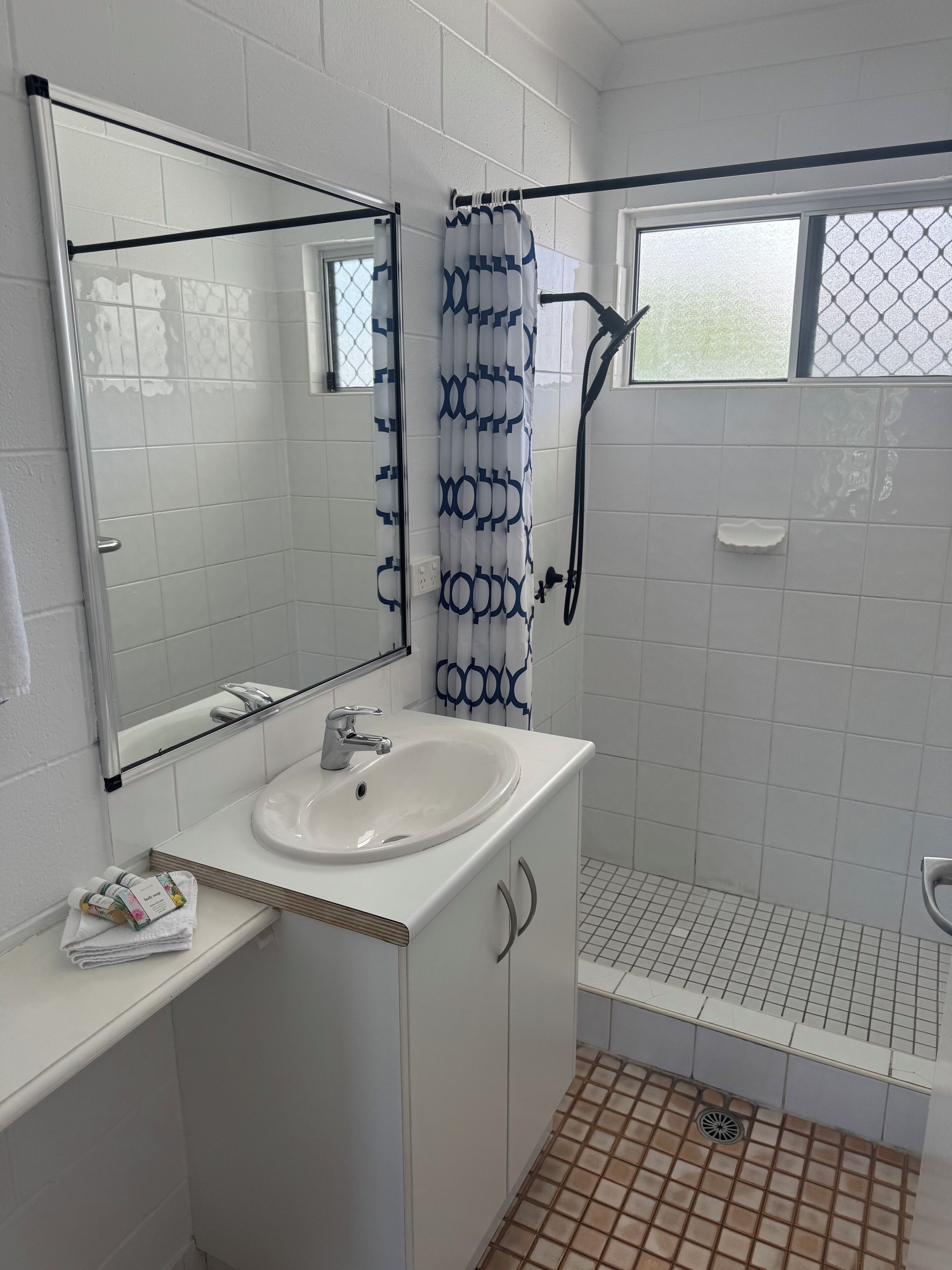 Un baño con lavamanos blanco, espejo y ducha.