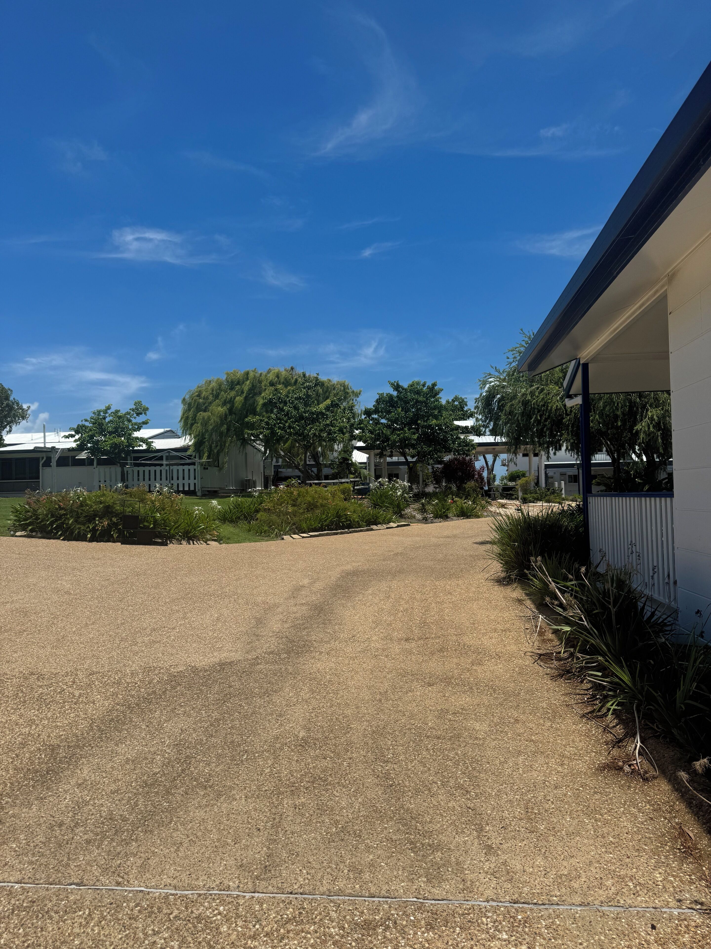 A gravel driveway leading to a building with a covered porch.