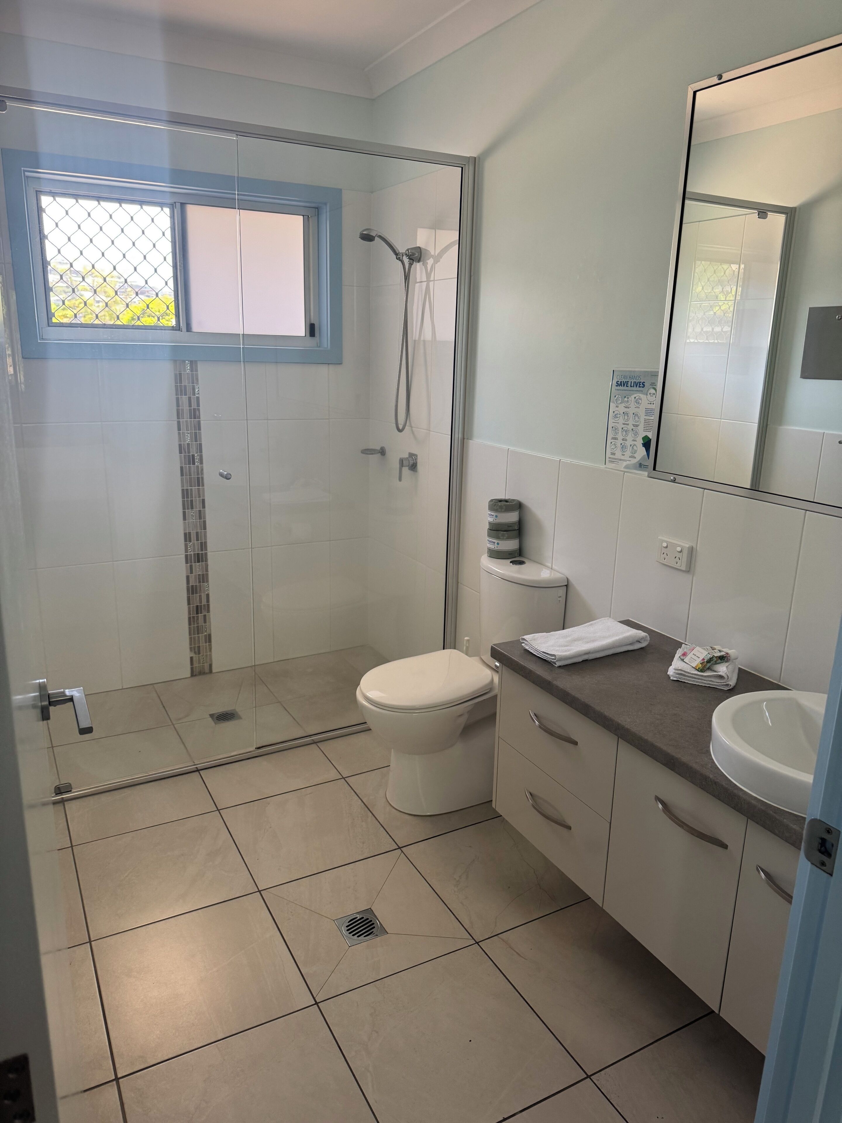A modern bathroom with a glass-enclosed shower, a toilet, a sink, and a mirror.