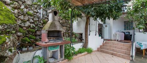 A stone wall, a rustic outdoor oven, a staircase, and a covered seating area.
