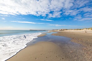 A beach with a wide sandy shore, gentle waves, and a clear sky.