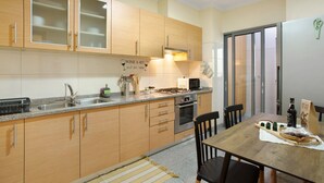 Une cuisine avec des meubles de rangement en bois, un évier en acier inoxydable, un four à micro-ondes et une table à manger avec des chaises.