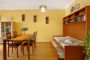 A room with a wooden dining table, chairs, a sofa, a bookshelf, and a hanging light fixture. - Apartment 'Casa Da Vila' with Sea View, Balcony and Wi-Fi (Santa Cruz)