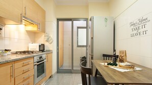 Une cuisine moderne avec des meubles en bois, des appareils électroménagers en acier inoxydable et un coin repas comprenant une table et des chaises en bois.