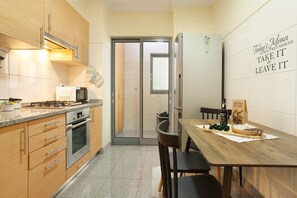 Una cocina moderna con armarios de madera, electrodomésticos de acero inoxidable y un comedor con mesa y sillas de madera.