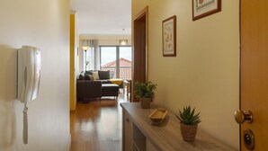 Un couloir avec un téléphone, une porte en bois et une plante en pot.