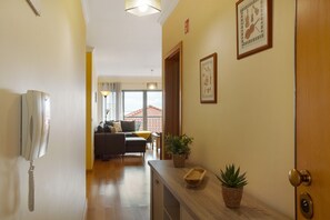 Un pasillo con un teléfono, una puerta de madera y una planta en maceta.