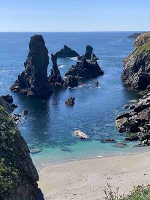 A coastal landscape with rocky formations and clear blue water.