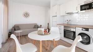 Una cocina moderna con armarios blancos, horno empotrado y lavadora.
