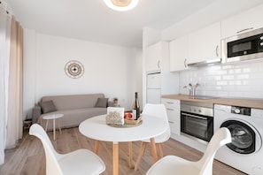 Una cocina moderna con armarios blancos, horno empotrado y lavadora.