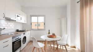 Una cocina moderna con lavadora, horno y comedor con mesa y sillas.