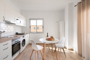 Une cuisine moderne équipée d’un lave-linge, d’un four et d’un coin repas avec une table et des chaises.
