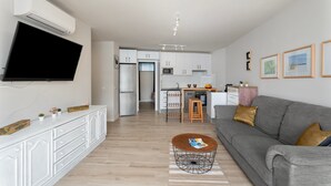 Ein modernes Wohnzimmer mit grauem Sofa, Couchtisch und Wand-Fernseher.