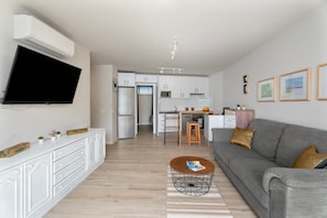 Ett modernt vardagsrum med en grå soffa, ett soffbord och en platt-TV som är monterad på väggen.
