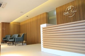 Un espace d’accueil avec un mur en lambris de bois, un comptoir d’accueil et trois chaises bleues.