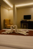 Una habitación de hotel con una cama, televisión, escritorio y dos sillas.
