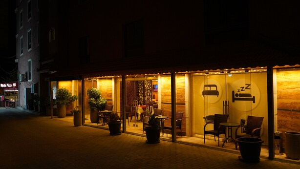 A hotel with a cozy outdoor seating area, potted plants, and a visible sign for a nearby restaurant. - Petra Agora Hotel (Wadi Musa)