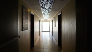 A hallway with a modern ceiling design, a view to a bright room, and a tiled floor. - Petra Agora Hotel (Wadi Musa)