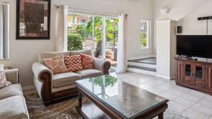 A living room with a sofa, coffee table, and TV. - Beautiful Townhome at Lake Barkley With Pool View! (Kissimmee)