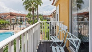 A balcony with a pool view, white railings, and palm trees. - Beautiful Townhome at Lake Barkley With Pool View! (Kissimmee)