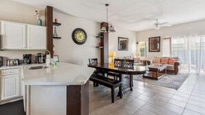 A modern kitchen with a central island, dining area with chairs, and a living room with a sofa and coffee table. - Beautiful Townhome at Lake Barkley With Pool View! (Kissimmee)