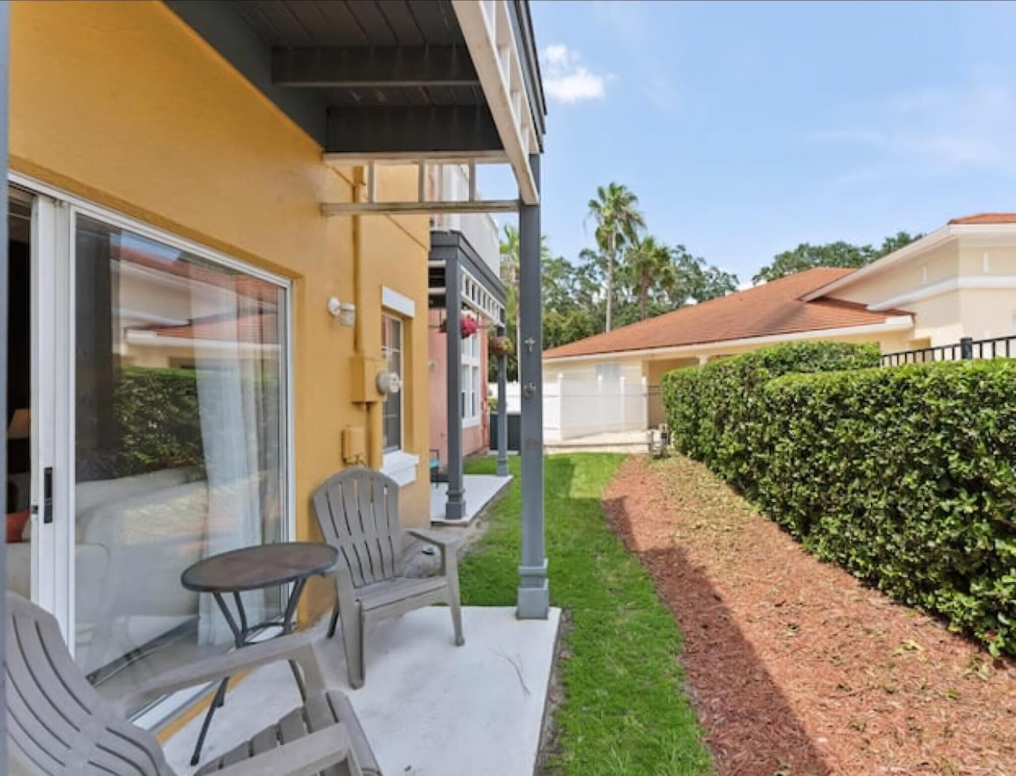 A patio with outdoor furniture, a covered area, and a well-maintained hedge.
