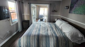 Une chambre d’hôtel avec un grand lit, une télévision, un balcon et un tableau au mur.