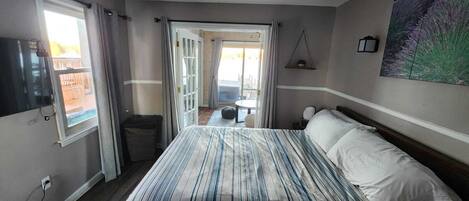 Habitación de hotel con una cama grande, televisión, balcón y un cuadro en la pared.