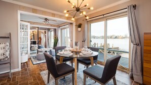 Un coin repas comprenant une table ronde, quatre chaises et une vue sur un plan d’eau, grâce à de grandes fenêtres.